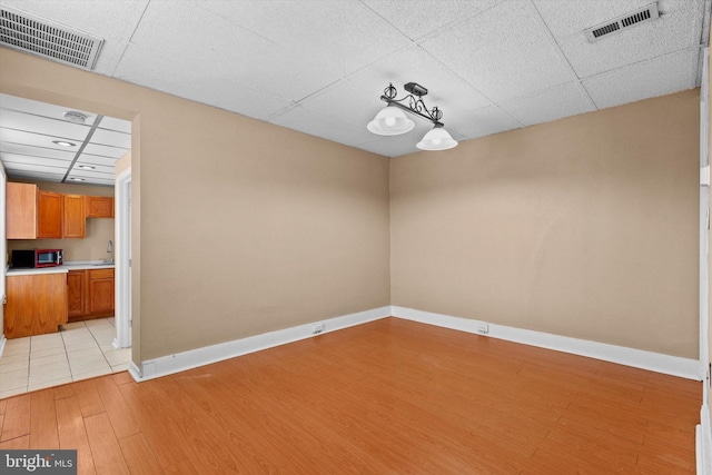 unfurnished room featuring a drop ceiling, sink, and light hardwood / wood-style flooring