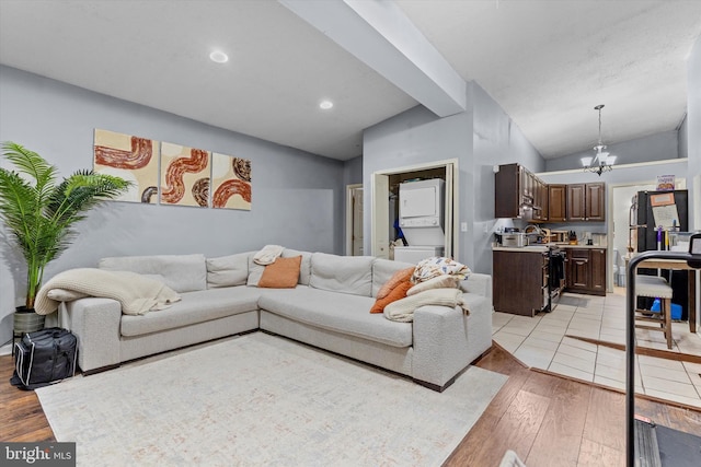 living room featuring an inviting chandelier, vaulted ceiling, and light hardwood / wood-style floors