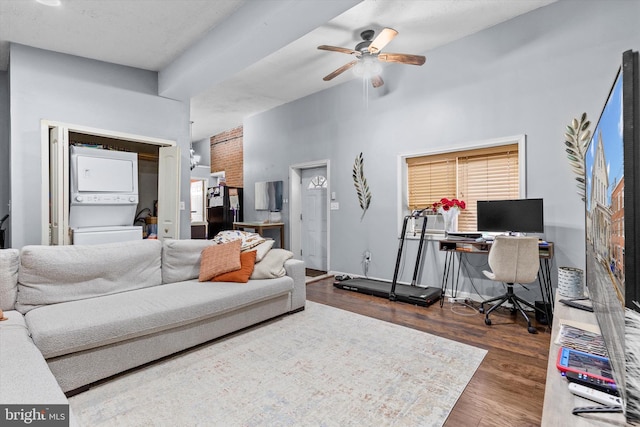 living room with stacked washing maching and dryer, dark hardwood / wood-style floors, and ceiling fan