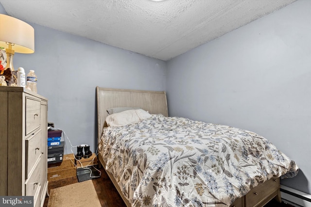 bedroom with a baseboard heating unit and a textured ceiling