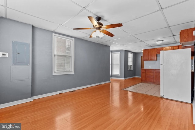 unfurnished living room featuring ceiling fan, a paneled ceiling, electric panel, and light wood-type flooring