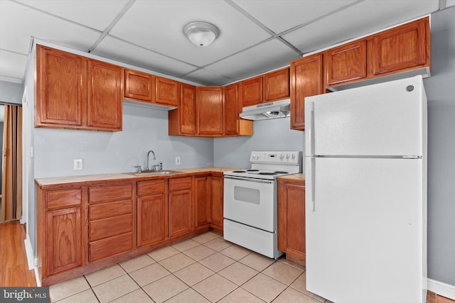 kitchen featuring sink, white appliances, a paneled ceiling, and light tile patterned floors