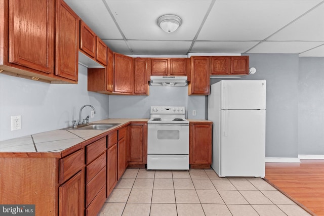 kitchen featuring sink, tile countertops, light tile patterned floors, white appliances, and a drop ceiling