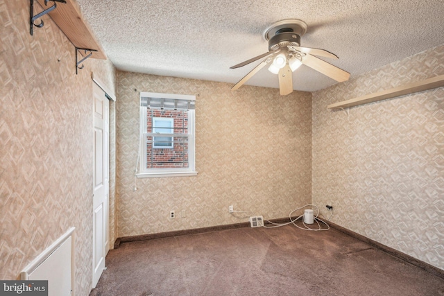 carpeted spare room with a textured ceiling and ceiling fan