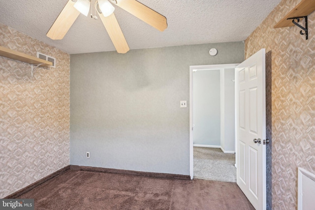 spare room with ceiling fan, dark carpet, and a textured ceiling