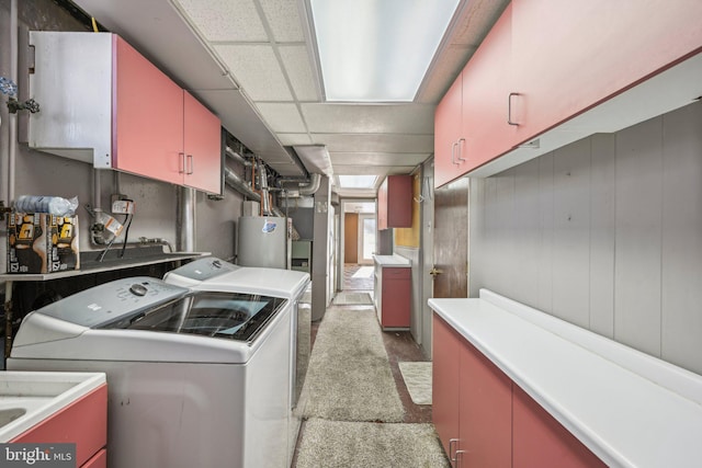 washroom with water heater, sink, washer and clothes dryer, and cabinets