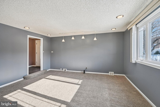 spare room with a textured ceiling and carpet