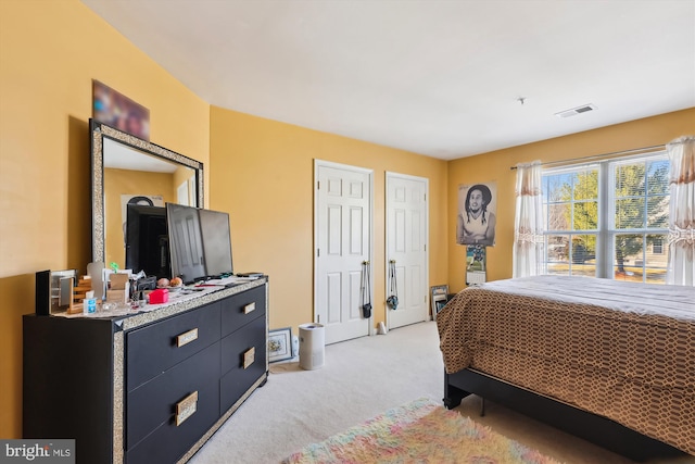 bedroom with light carpet and two closets