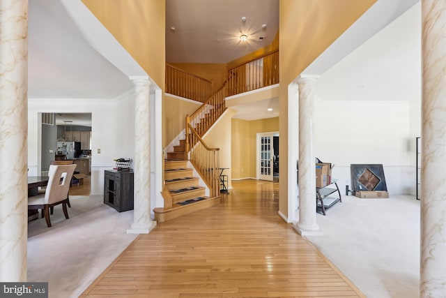 foyer entrance with hardwood / wood-style floors, a towering ceiling, and decorative columns