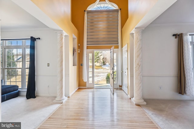 entryway featuring decorative columns, plenty of natural light, light hardwood / wood-style flooring, and crown molding