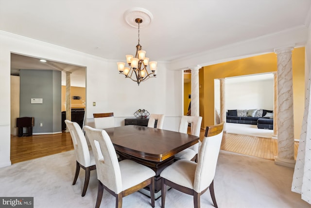 carpeted dining space with decorative columns, crown molding, and a notable chandelier