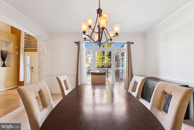 dining area with an inviting chandelier, light hardwood / wood-style floors, decorative columns, french doors, and crown molding