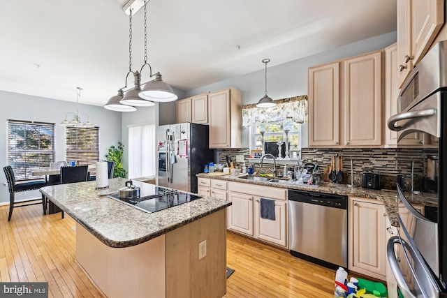 kitchen featuring a kitchen island, sink, hanging light fixtures, appliances with stainless steel finishes, and a kitchen breakfast bar