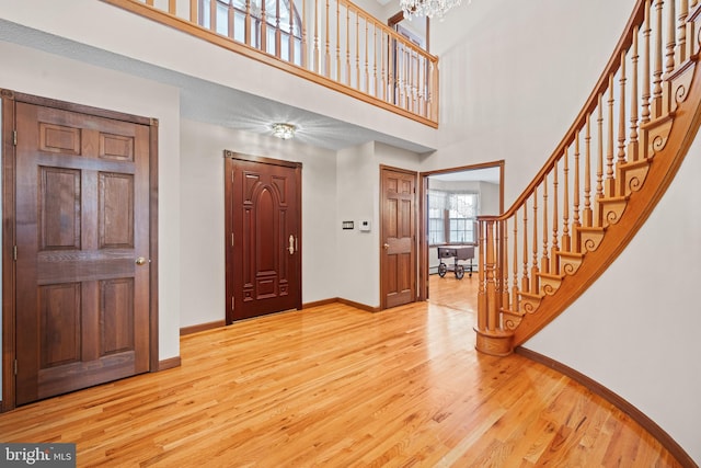 entrance foyer with light hardwood / wood-style floors, a chandelier, and a towering ceiling