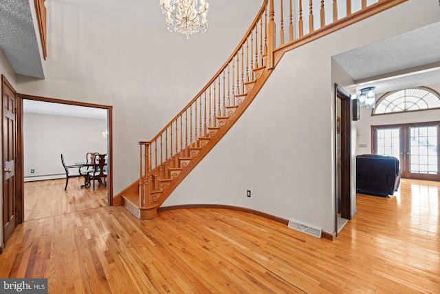 entryway featuring a baseboard radiator, a textured ceiling, light hardwood / wood-style flooring, and a chandelier