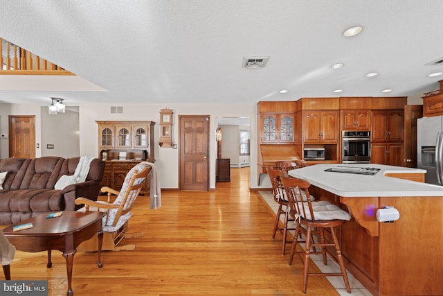 kitchen featuring stainless steel appliances, a kitchen breakfast bar, light wood-type flooring, a textured ceiling, and a center island