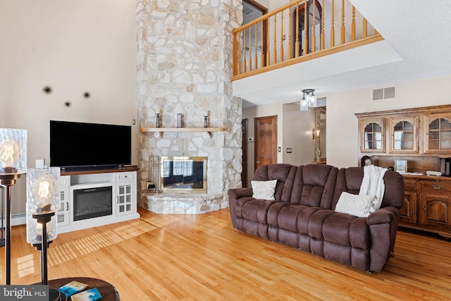 living room featuring light hardwood / wood-style floors, a fireplace, and a high ceiling