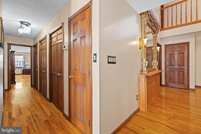 hallway with a textured ceiling and light hardwood / wood-style floors