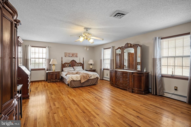 bedroom with a baseboard heating unit, ceiling fan, a textured ceiling, and light wood-type flooring