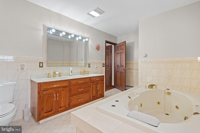 bathroom featuring tile patterned floors, vanity, tile walls, toilet, and tiled bath