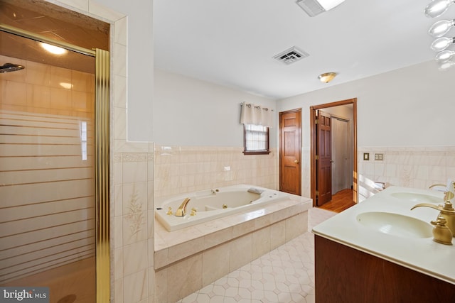 bathroom featuring independent shower and bath, tile patterned flooring, tile walls, and vanity