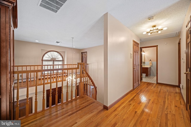 hall featuring a baseboard radiator, a textured ceiling, and light hardwood / wood-style flooring