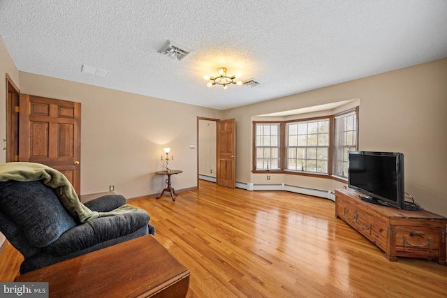 living room featuring a textured ceiling, light hardwood / wood-style floors, and a baseboard radiator