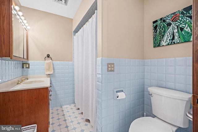 bathroom featuring toilet, tile patterned flooring, tile walls, a shower with curtain, and vanity