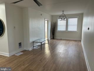 unfurnished dining area with dark hardwood / wood-style flooring and ceiling fan with notable chandelier