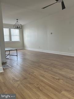 spare room with ceiling fan with notable chandelier and hardwood / wood-style flooring