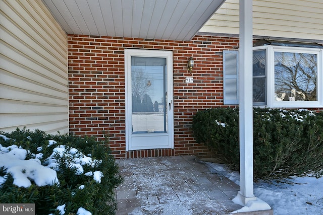 snow covered property entrance with a patio area