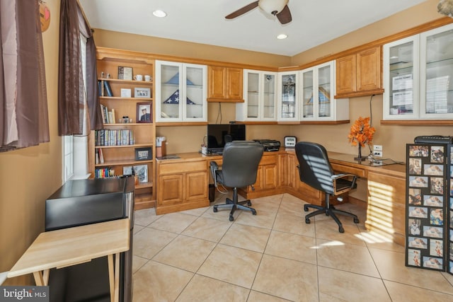 office with built in desk, ceiling fan, and light tile patterned flooring