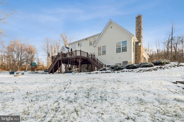 snow covered rear of property featuring a playground and a deck