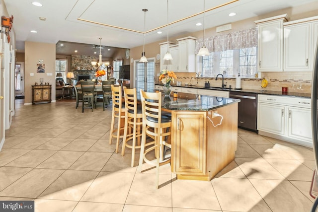 kitchen with dishwasher, pendant lighting, a kitchen island, white cabinetry, and light tile patterned floors