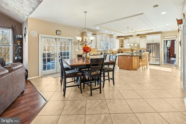 tiled dining area featuring french doors and a tray ceiling