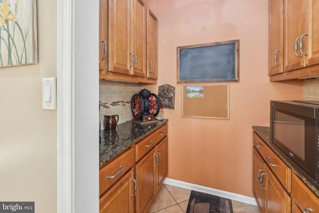 kitchen with light tile patterned floors, backsplash, and dark stone counters