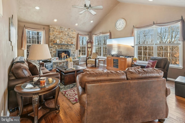 living room featuring ceiling fan, high vaulted ceiling, a fireplace, and hardwood / wood-style flooring