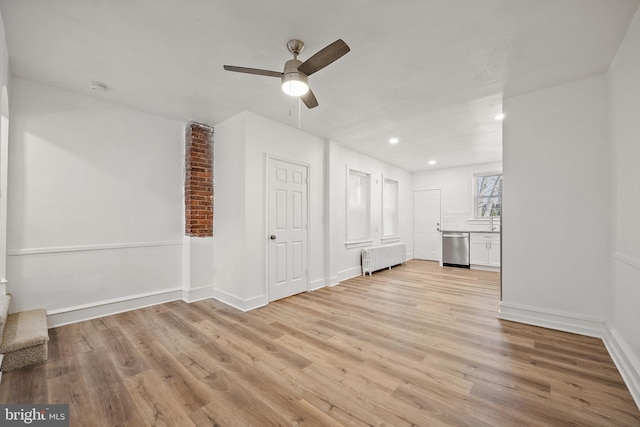 unfurnished living room featuring radiator heating unit, light wood-type flooring, and ceiling fan