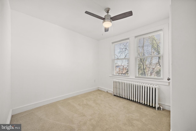 carpeted empty room featuring radiator and ceiling fan