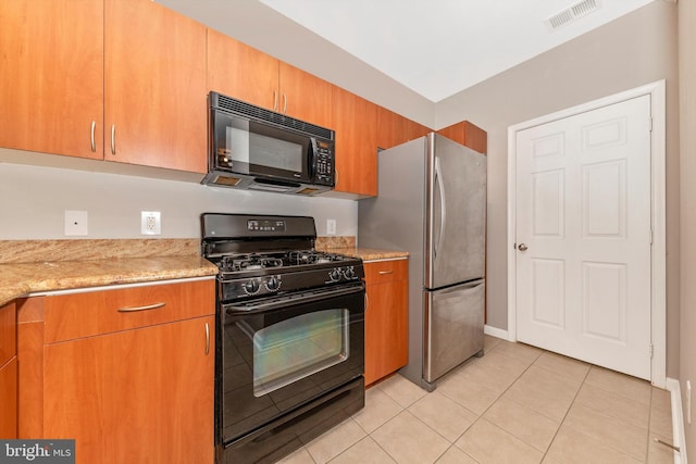 kitchen with light tile patterned flooring, black appliances, and light stone counters