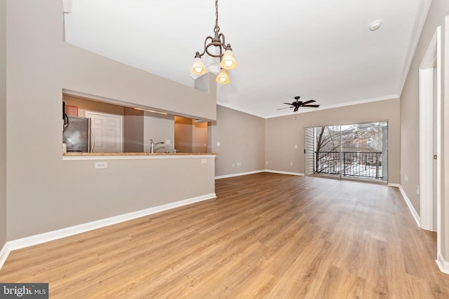 unfurnished living room featuring light wood-type flooring, ceiling fan with notable chandelier, crown molding, and sink