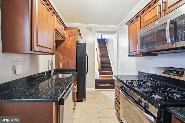 kitchen with crown molding, light tile patterned floors, sink, dark stone countertops, and stainless steel appliances