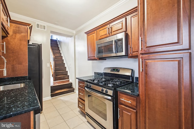 kitchen with sink, dark stone counters, light tile patterned flooring, ornamental molding, and stainless steel appliances