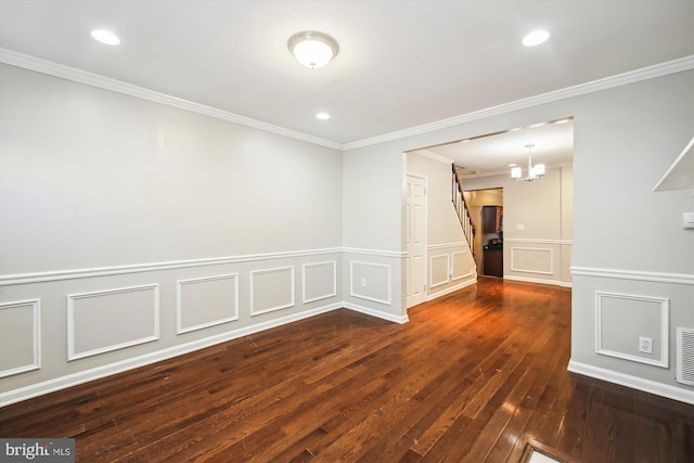 empty room featuring ornamental molding, dark hardwood / wood-style floors, and an inviting chandelier