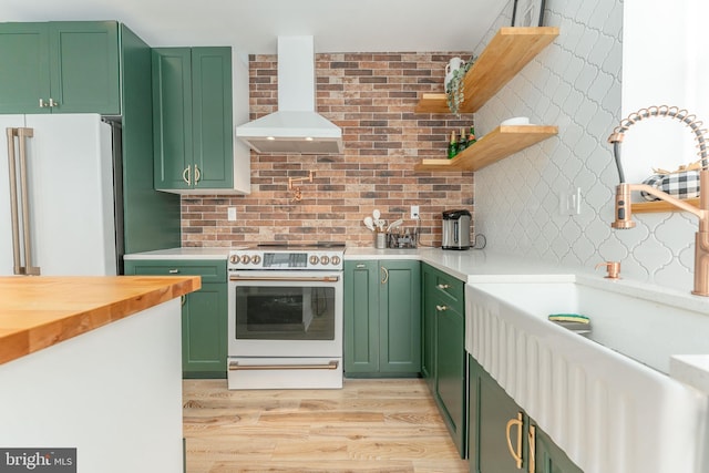 kitchen featuring green cabinets, light hardwood / wood-style flooring, wall chimney exhaust hood, and high quality appliances