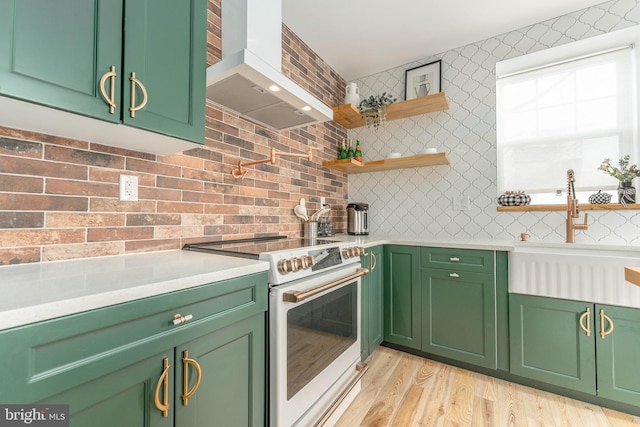 kitchen with light hardwood / wood-style floors, ventilation hood, green cabinetry, and white range with electric cooktop