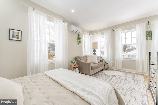 bedroom featuring light hardwood / wood-style floors and an AC wall unit