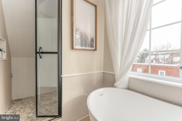 bathroom featuring a bath and tile walls