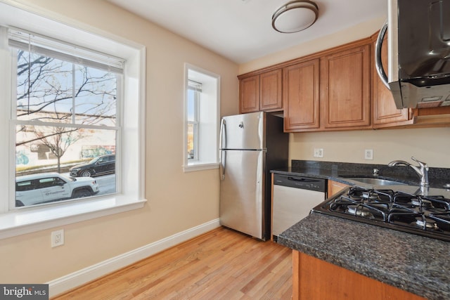 kitchen featuring light wood-type flooring, dark stone counters, sink, and stainless steel appliances