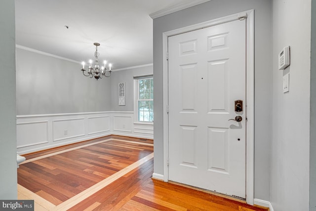 entryway featuring light hardwood / wood-style flooring, crown molding, and a notable chandelier